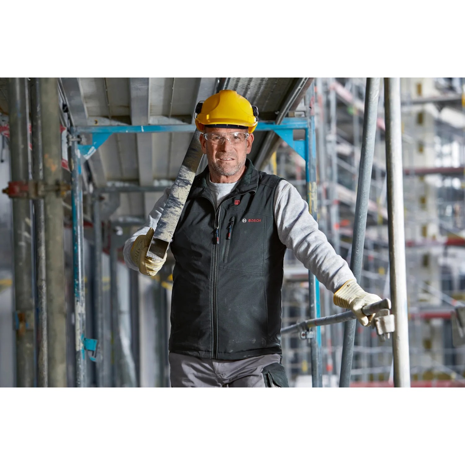 Bosch Professional Akku-Heizweste GHV 12+18V XA in Schwarz, getragen von Bauarbeiter mit Helm.