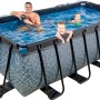 Rechteckiger, grauer EXIT Stone Pool mit Steinmuster, Abdeckung, Sandfilterpumpe, Wärmepumpe und Poolleiter. Personen im Pool.