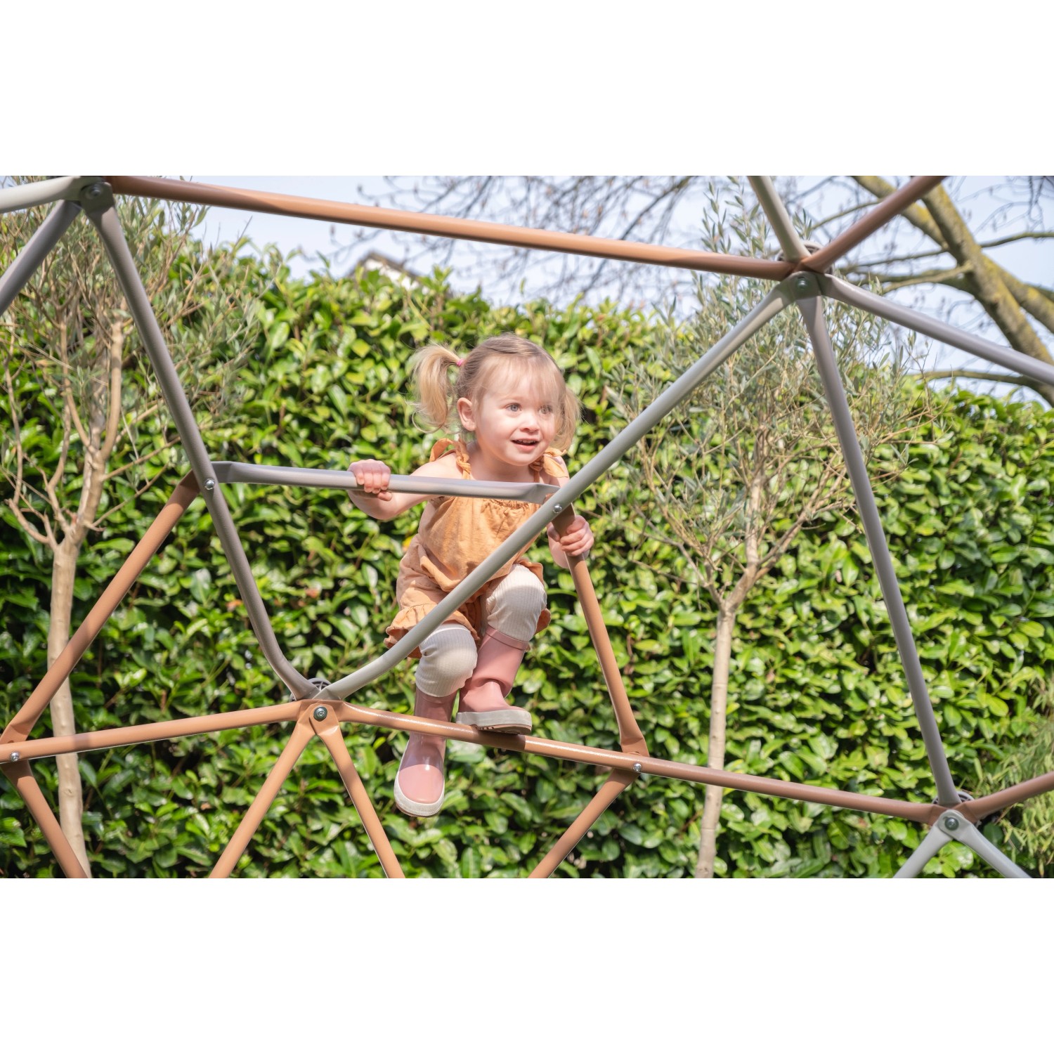 Kind klettert auf Exit Kletterkuppel Metal Climbing Dome (Ø 300 cm) im Garten.