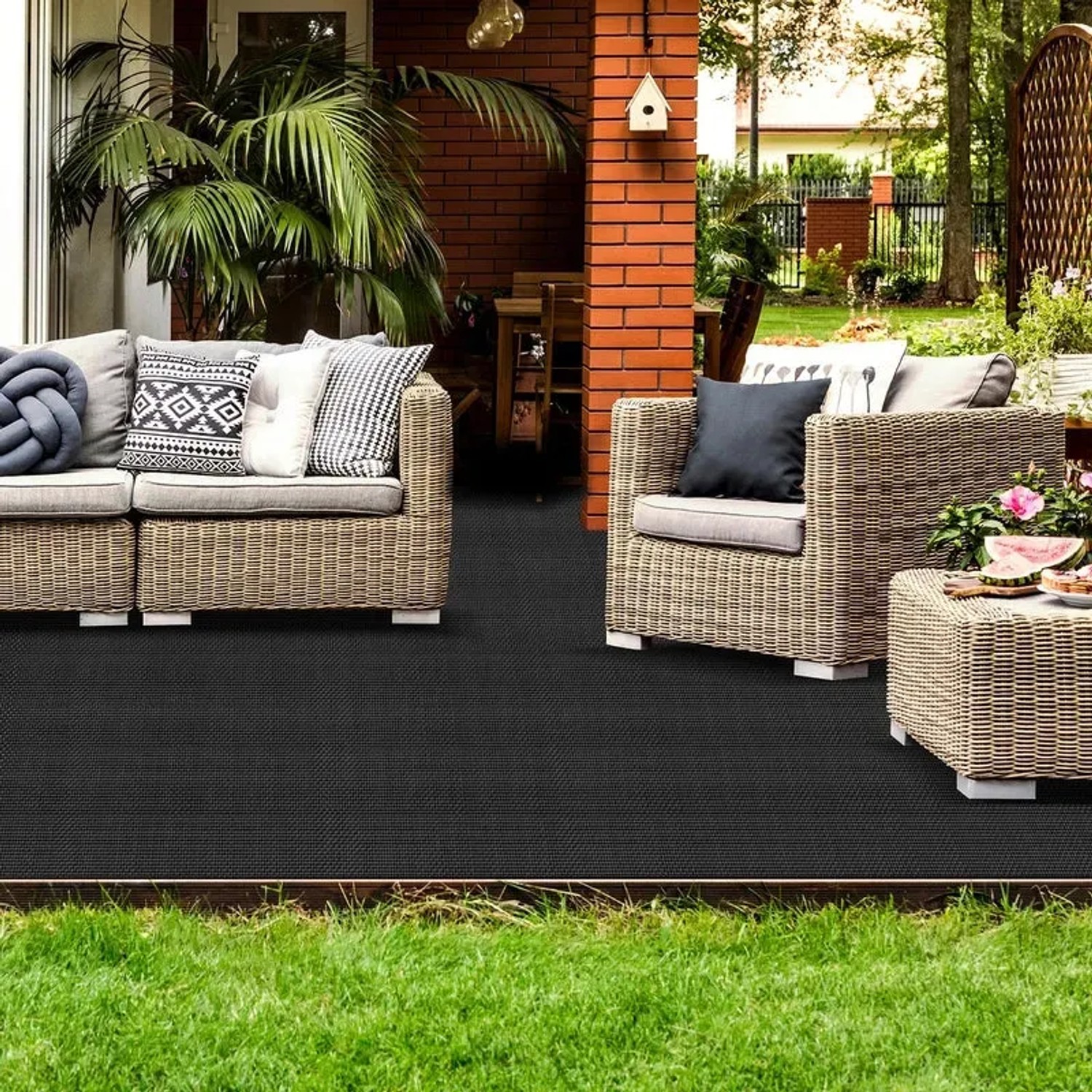 Schwarzer KARAT Outdoor Teppich Lucca auf Terrasse mit Gartenmöbeln.