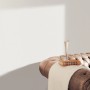 Weiße Erismann Vliestapete Spotlight InStyle an Wand über braunem Sofa mit Buch und Glas.