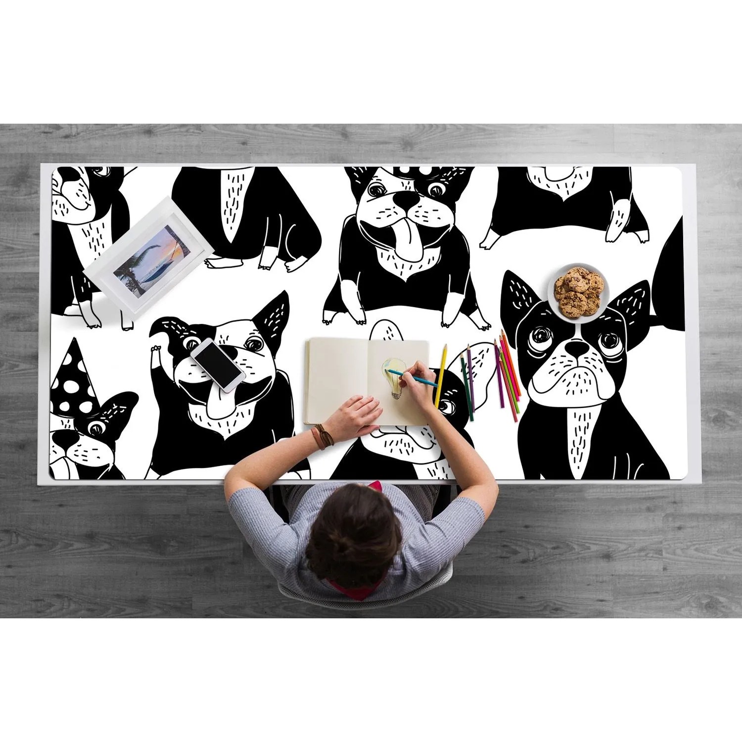 Weiße Schreibtischunterlage mit fröhlichen Cartoon-Hunden, darauf zeichnet eine Person. Schützt den Schreibtisch.