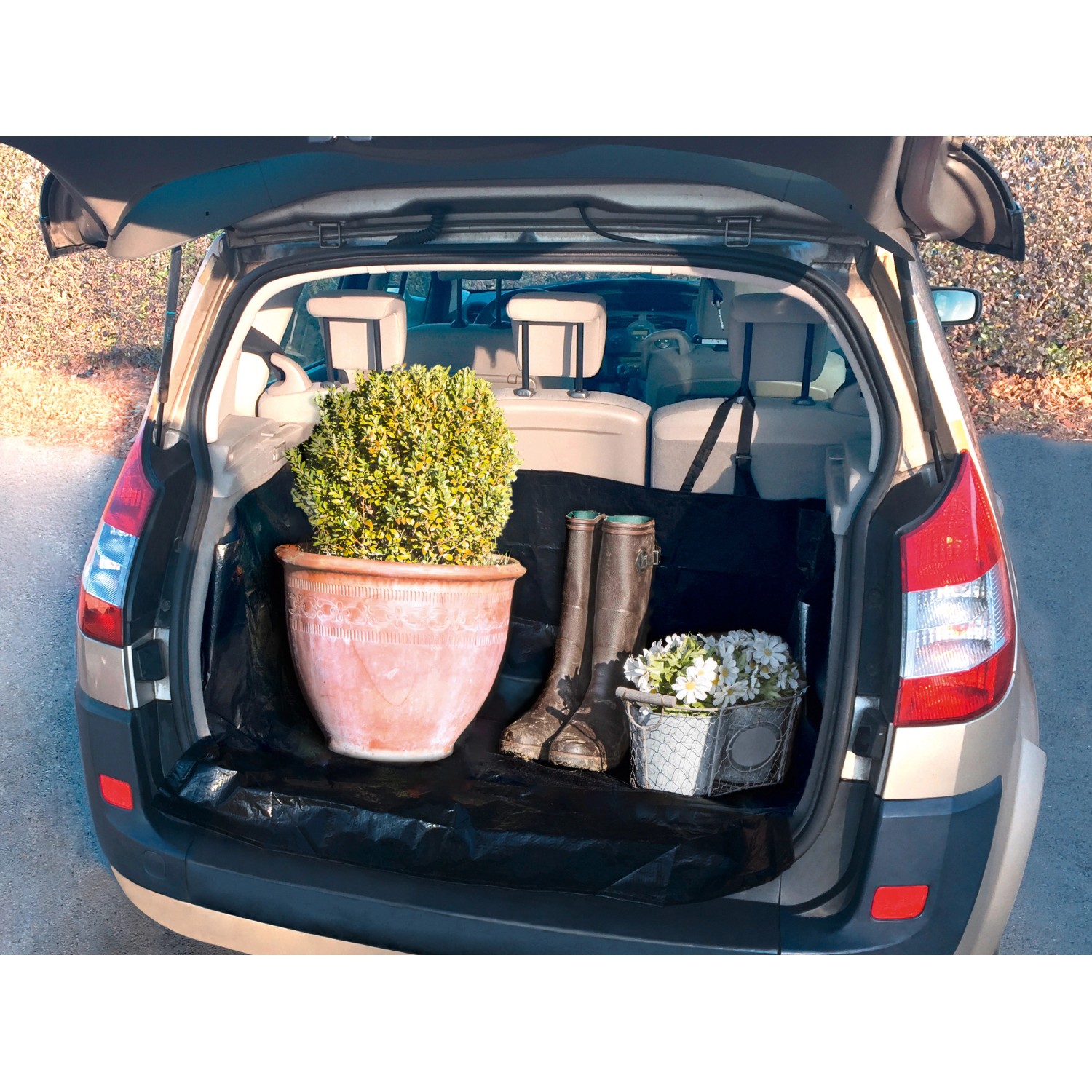 Schwarzer Kofferraumschutz aus Textil im Auto, mit Pflanze, Gummistiefeln und Blumen.