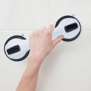 Hand hält weiß-schwarzen Relaxdays Haltegriff mit Saugnäpfen an weißer Fliesenwand. Bohrfreier Badhelfer aus Kunststoff.