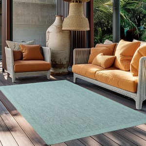 Blauer Ayyildiz Outdoor-Teppich Giza (160x230 cm) in Sisal-Optik auf einer Terrasse mit Möbeln.