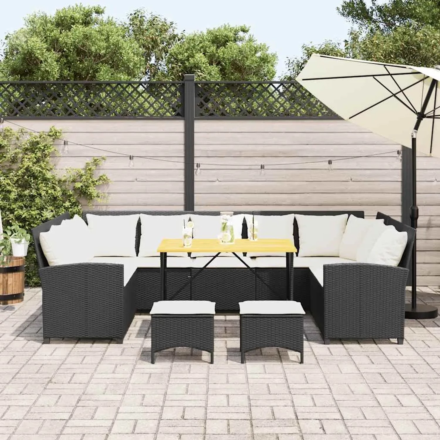 Schwarze 4-tlg. Garten-Sofagarnitur aus Rattan mit Tisch und Hockern, inklusive cremeweißen Kissen.