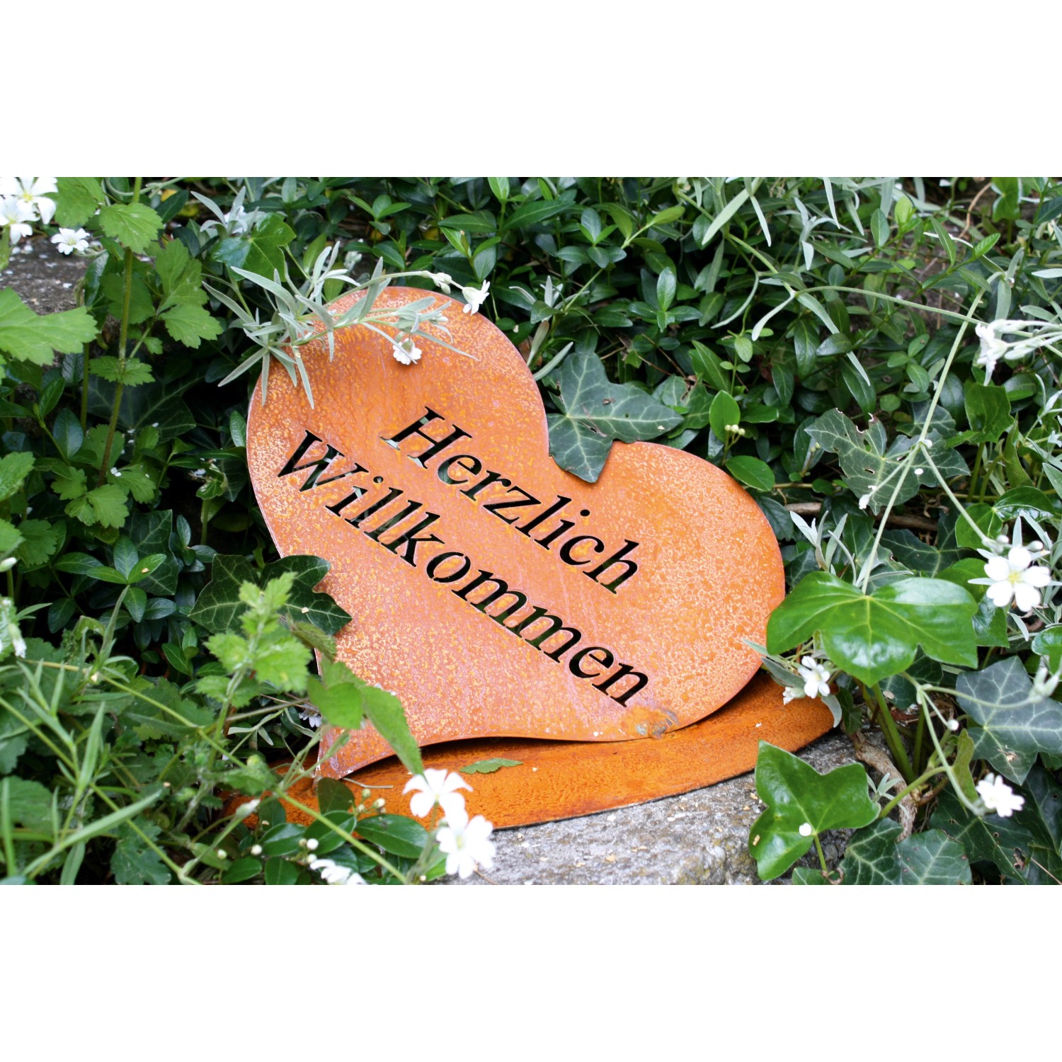 Rostbraunes Herz aus Metall mit "Herzlich Willkommen" Schriftzug als Gartendeko.
