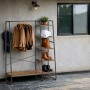 Songmics Kleiderständer Colten mit Schuhregal in Braun-Schwarz mit Kleidung, Handtüchern und Schuhen.