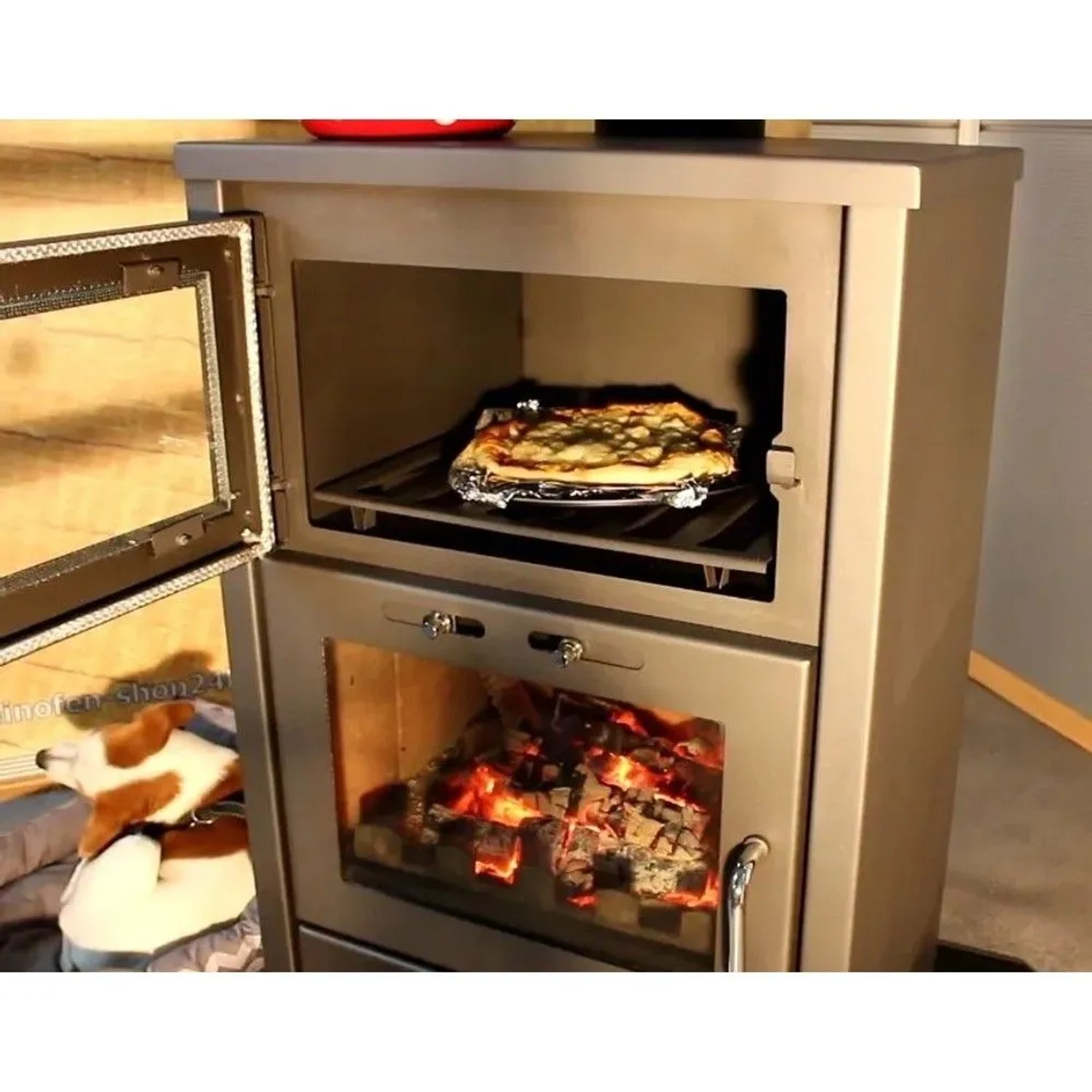 Schwarzer Victoria Kaminofen Triumph F mit Backfach, Pizza im oberen Ofen, Holz brennt im Brennraum.