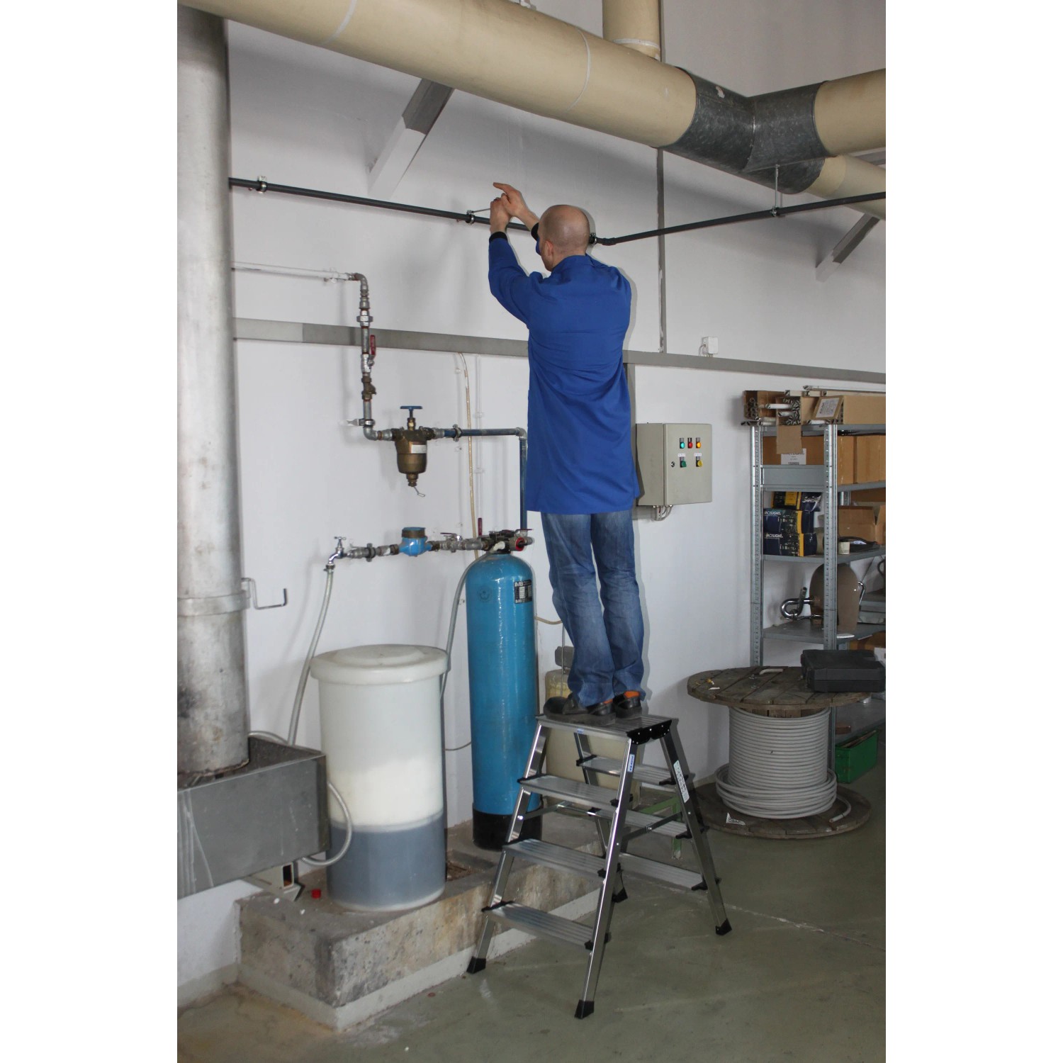 Krause Klapptritt Treppo: Mann auf Aluleiter bei Montagearbeiten im Innenraum.