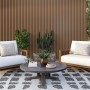 Terrasse mit Equipped WPC Wandpaneel Eiche Natur, Sesseln und Tisch. Dekor-Paneele für den Außenbereich.