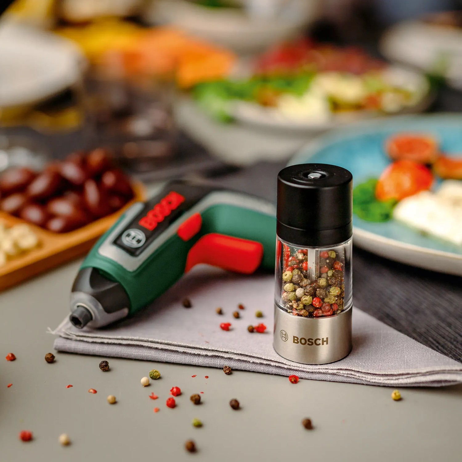 Bosch Akkuschrauber IXO 7 Set mit Gewürzmühle als Aufsatz auf gedecktem Tisch.