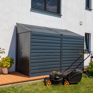 Graues Spacemaker Metall-Gerätehaus 4x10 mit Rasenmäher vor weißer Hauswand. Anlehn-Gerätehaus für Gartengeräte.