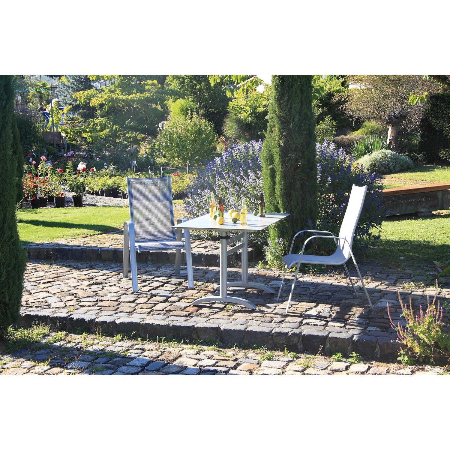 Rechteckiger Acamp Klapptisch Platin-Cemento (120x80 cm) mit zwei Stühlen im Garten.