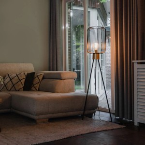 Schwarze QAZQA Design Stehlampe Mayelle mit goldenem Lampenschirm im Wohnzimmer.