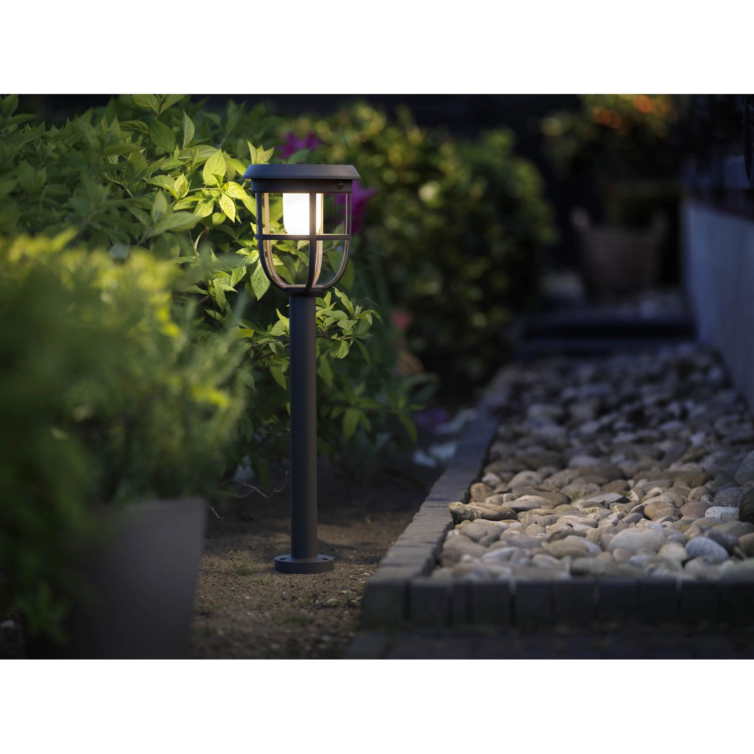 Philips Solar-Wegeleuchte Spiess Radii: Schwarze Sockelleuchte mit Solarpanel und warmweißem Licht im Garten.