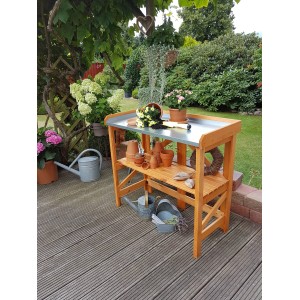 Klappbarer Pflanztisch aus Holz mit verzinkter Arbeitsfläche und Ablage im Garten.