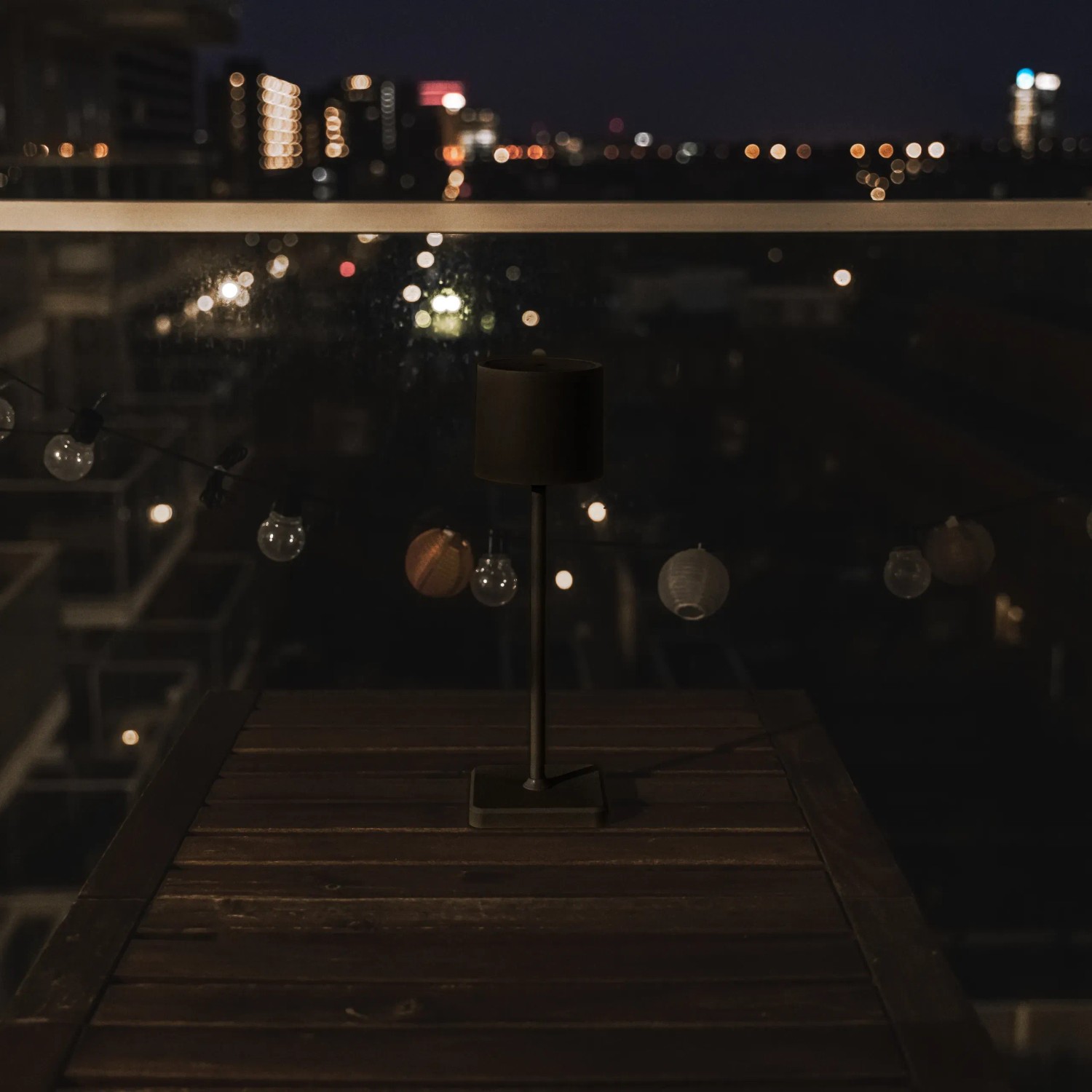 Schwarze, dimmbare LED Tischlampe für den Außenbereich mit CCT-Funktion auf einem Holztisch.