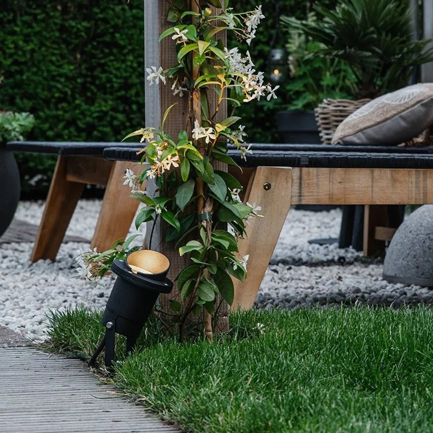 Schwarzer QAZQA Gartenstrahler Done mit Kabel und Stecker (IP65) im Garten mit Bepflanzung.