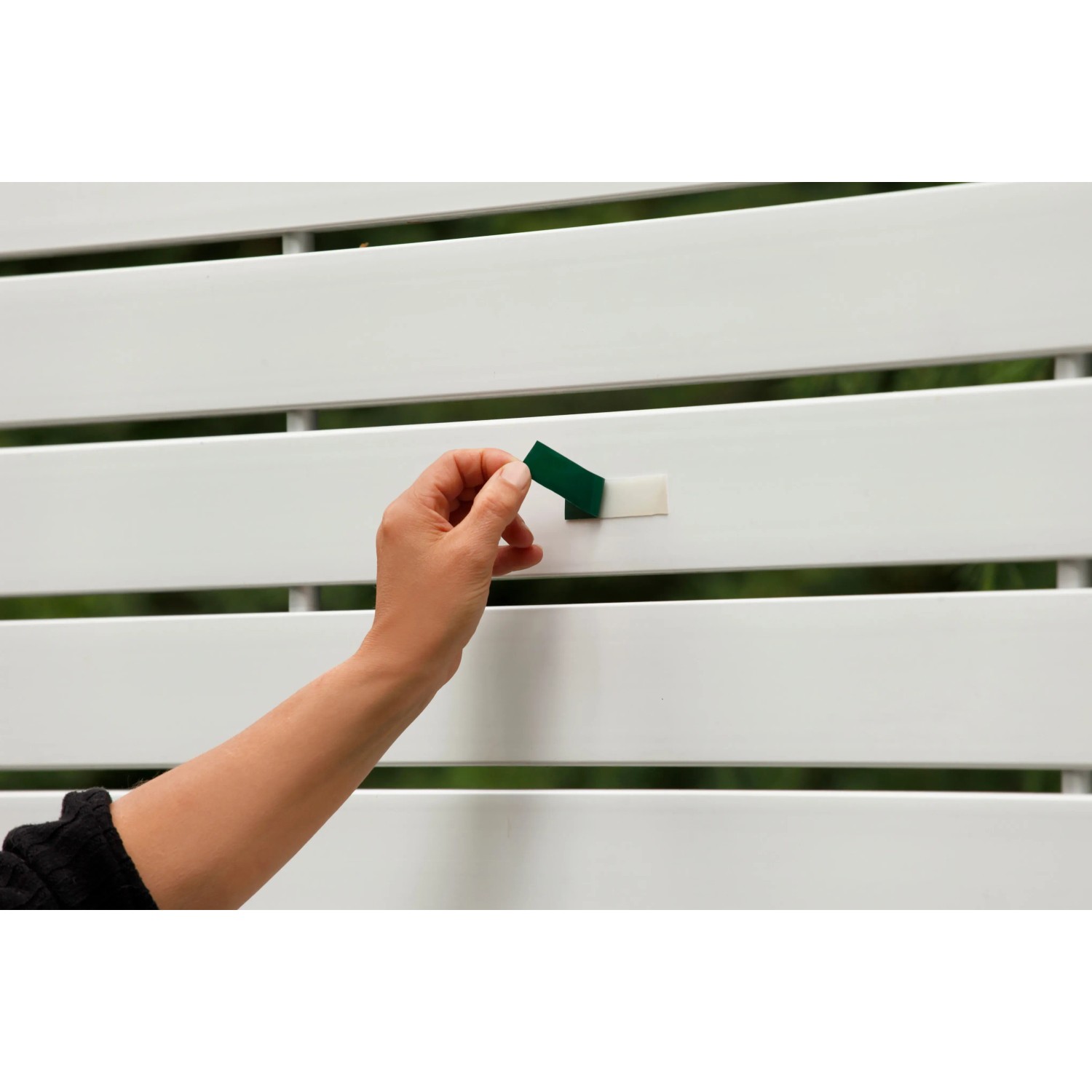 Anwendung Tesa Powerbond Montageband Outdoor (1,5m x 19mm) auf weißem Zaun.