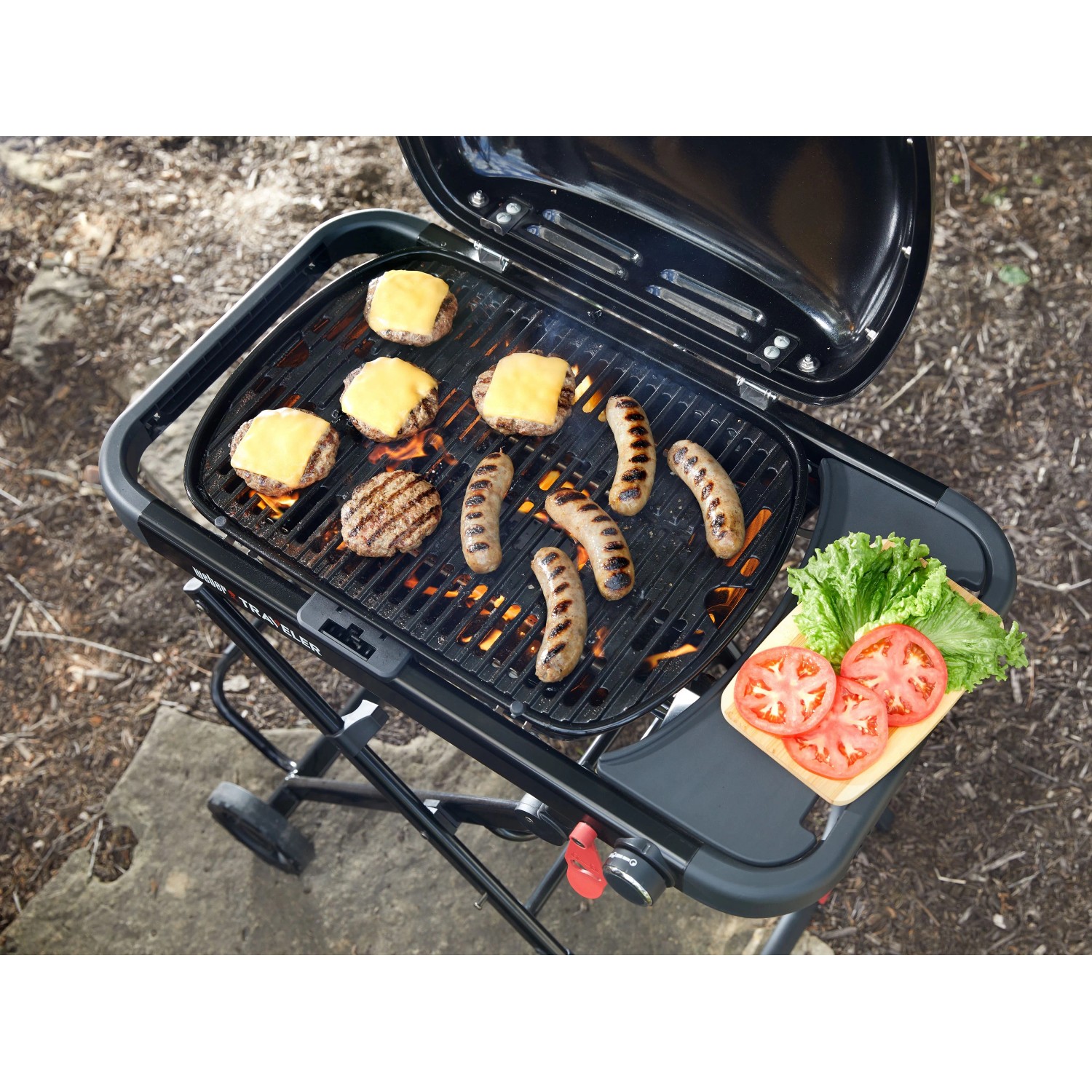 Schwarzer Weber Gasgrill Traveler Compact mit Grillgut und Beilagen auf Seitentisch.