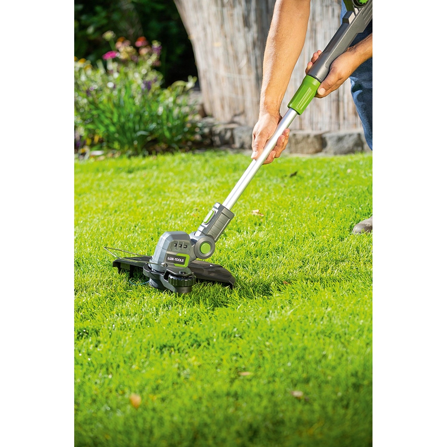 LUX Akku-Rasentrimmer A-RT-20/25 im Einsatz auf Rasenfläche. Akku-Trimmer mit Teleskopstiel und Pflanzenschutzbügel.