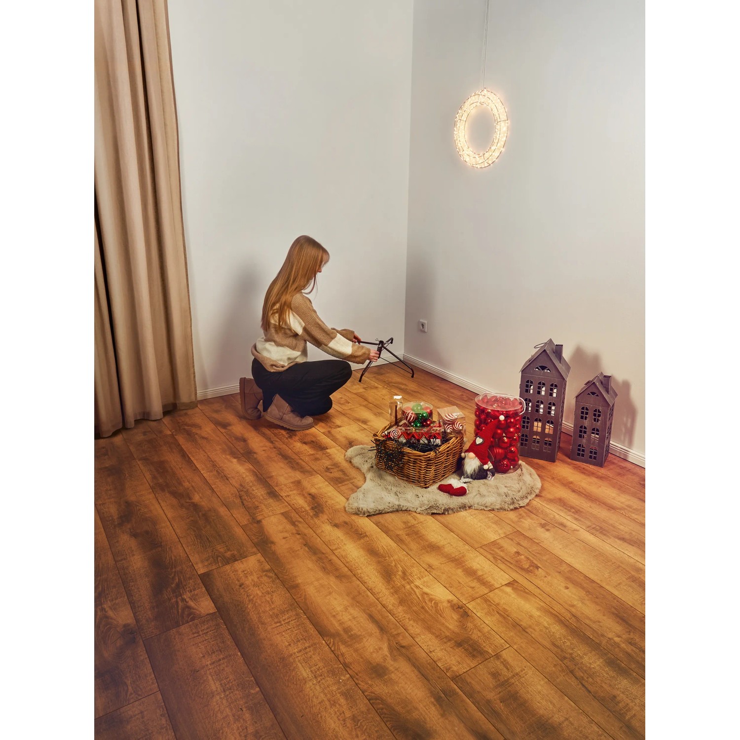 Frau baut künstlichen Weihnachtsbaum Nagano 180cm mit LED-Beleuchtung auf. Deko-Elemente im Raum.