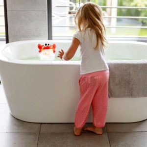 Kind spielt mit rot-orangem Relaxdays Badewannenspielzeug Krabbe, das Schaum und Musik erzeugt. Badespaß für Kinder.