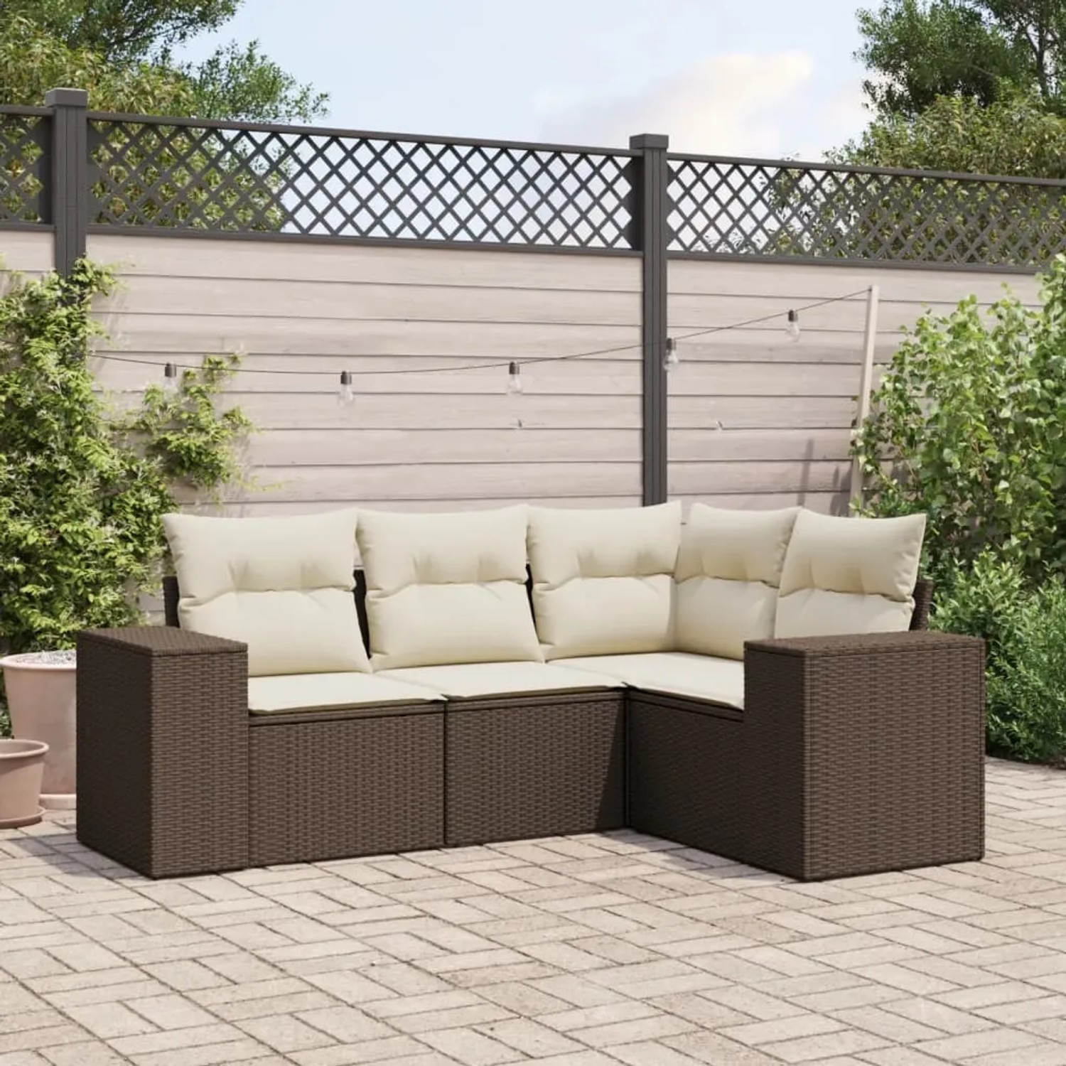 Braune 4-tlg. vidaXL Garten-Sofagarnitur aus Rattan mit cremefarbenen Kissen im Garten.