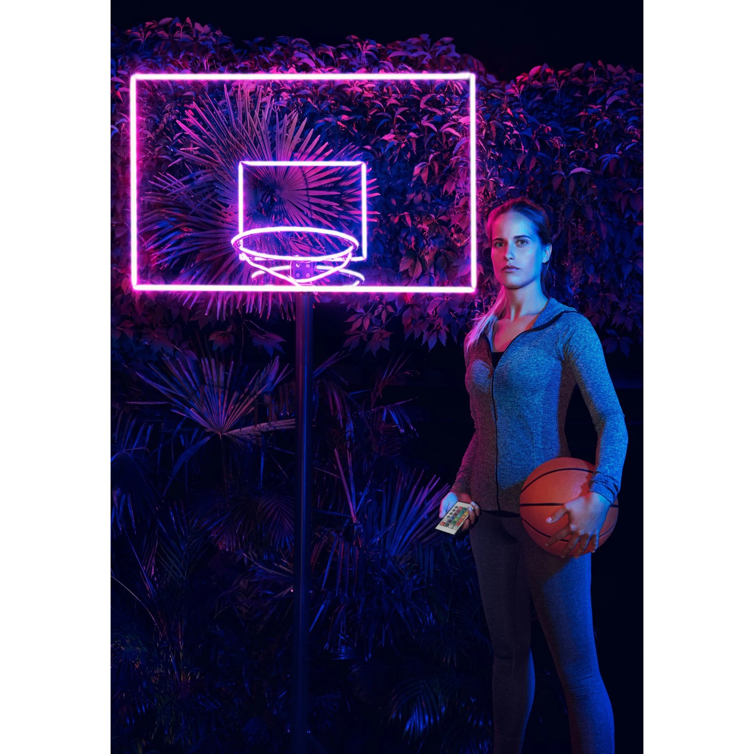 Frau mit Basketball vor leuchtendem LED-Streifen Neon Digitalflex Basketballkorb.