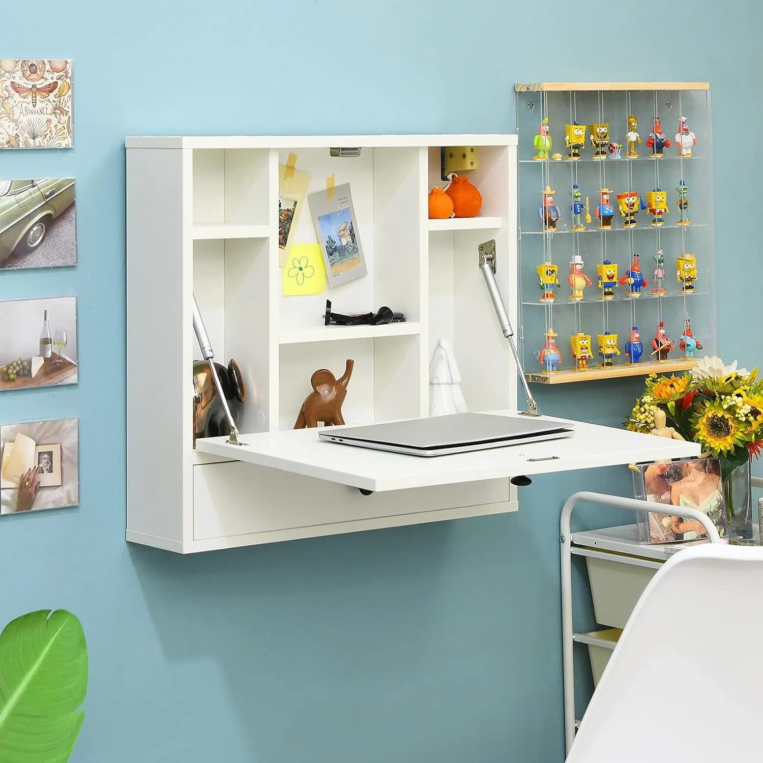 Weißer Costway Wandklapptisch mit geöffneter Tischplatte, Ablagefächern und Schublade, Laptop darauf, an blauer Wand.