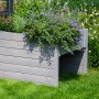 Graue Dobar Mährobotergarage mit Pflanzkasten, bepflanzt mit Blumen, im Garten.