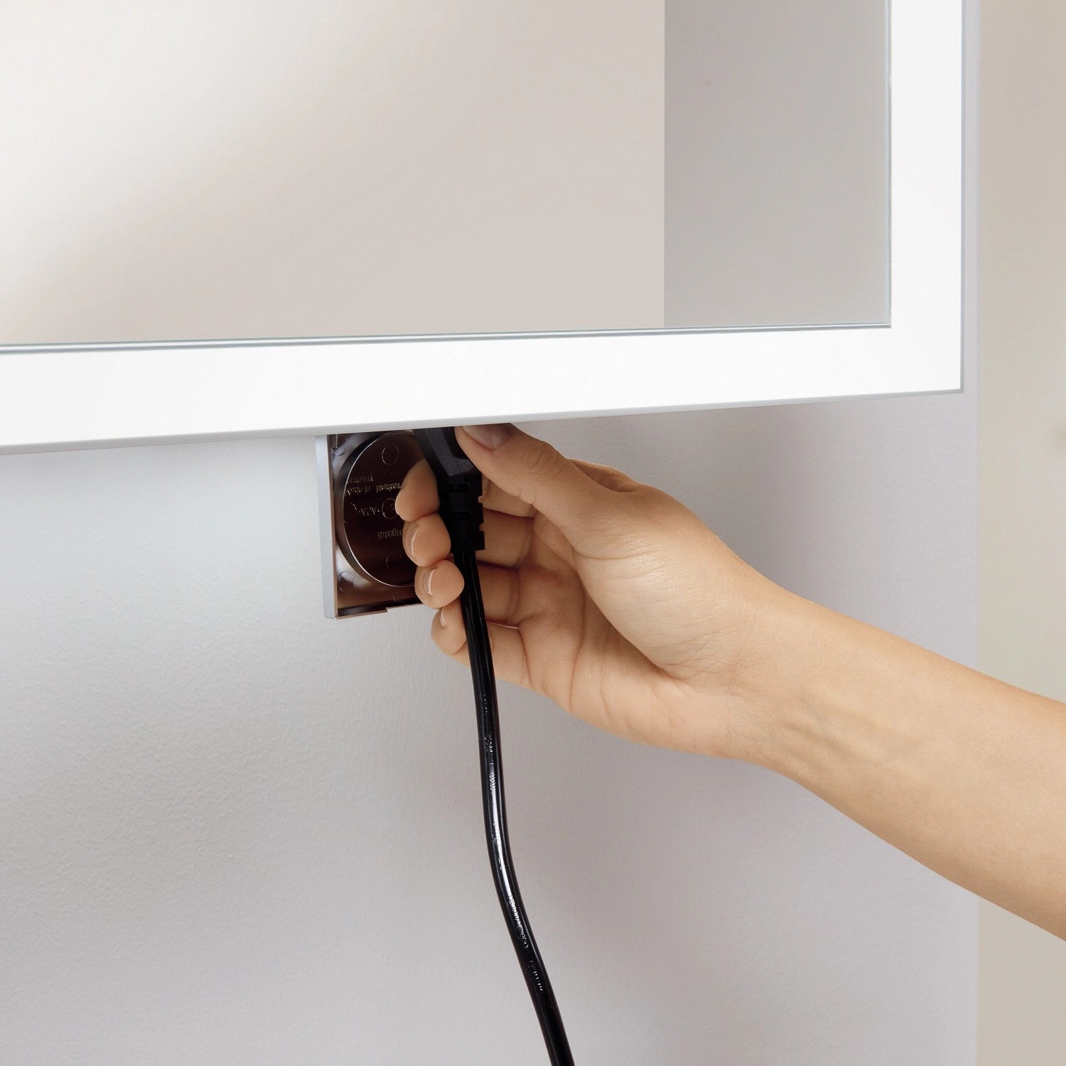 Detailaufnahme: Hand steckt Stecker in Steckdose des Villeroy & Boch Spiegelschranks My View Now.