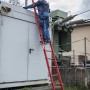 Mann auf roter PROREGAL GFK Anlegeleiter (8 Sprossen) vor Transformatorstation. Leiter für Arbeiten an spannungsführenden Teilen.
