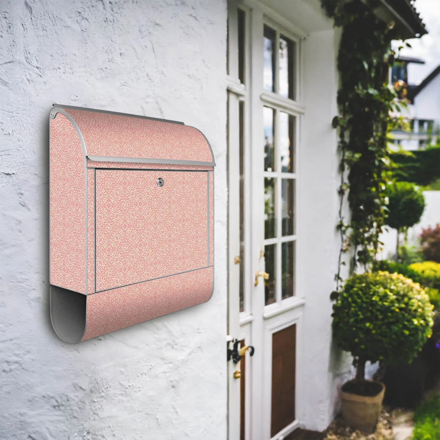 Banjado Design Briefkasten Silber mit rosa Arabesque Motiv und Zeitungsfach an Hauswand.