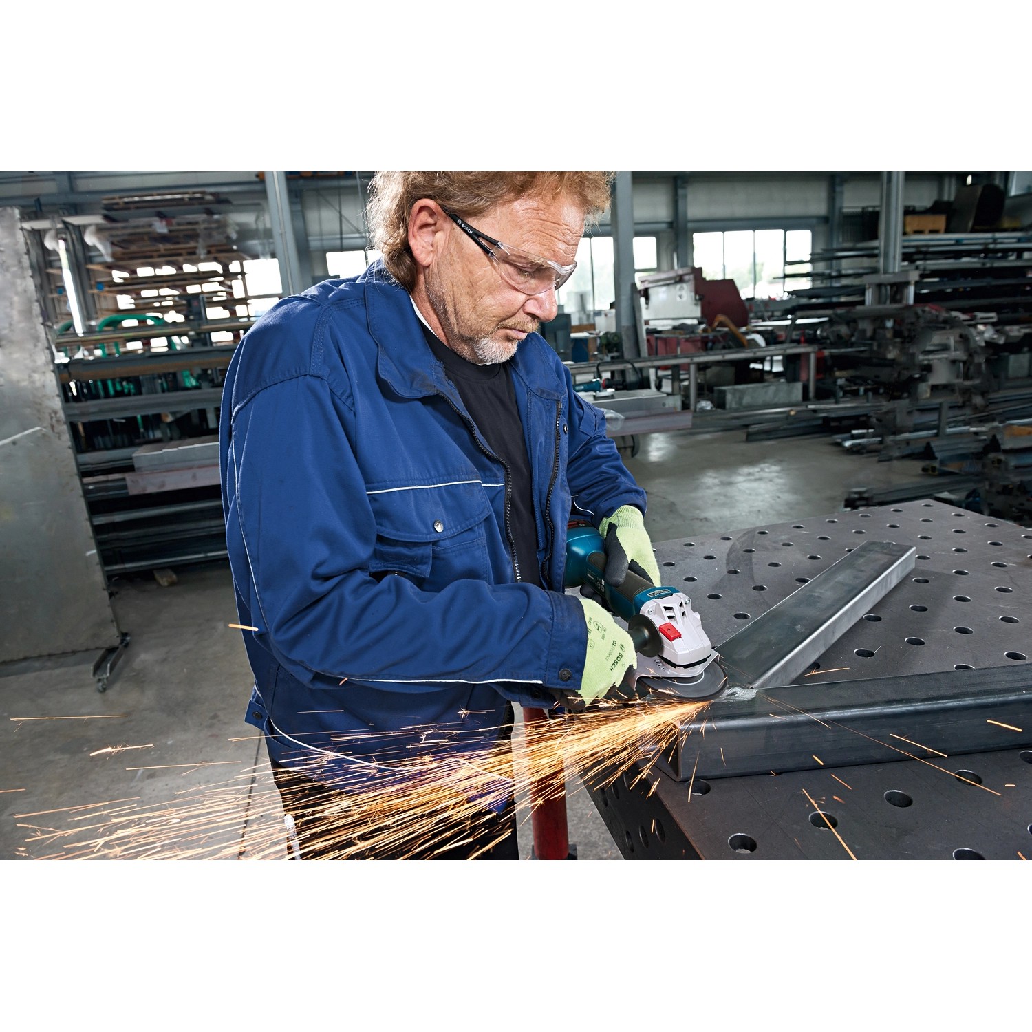 Mann schleift Metall mit Akku-Winkelschleifer GWS 18V-10 von Bosch Professional, Funken fliegen.
