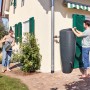 Garantia 2in1 Wasserbehälter 300 l in Grau mit Pflanzschale im Garten, Frau gießt Blumen.