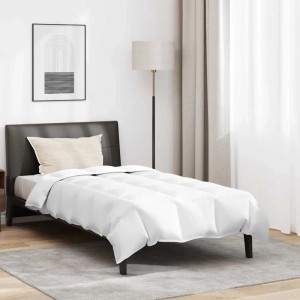 Weiße Winterbettdecke und Kissen auf einem Einzelbett. Gesteppte Daunenfeder-Decke für gemütlichen Schlafzimmer-Komfort.