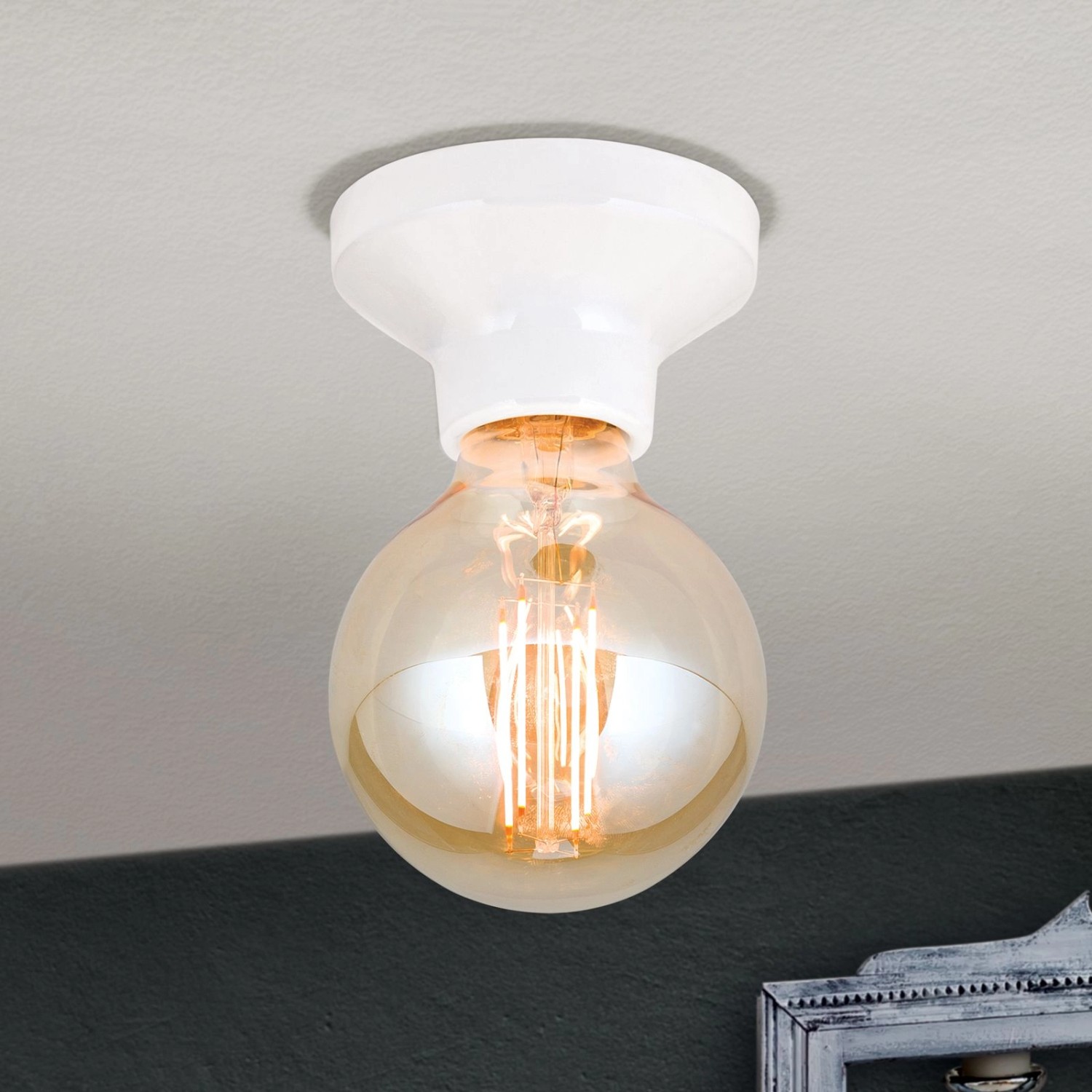 Weiße Orion Keramik Deckenleuchte mit E27 Fassung und Glühbirne an der Decke.