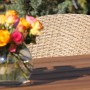 Acamp Atacama Gartenstuhl: Detailansicht von Geflecht und Teakholz mit Blumenvase.