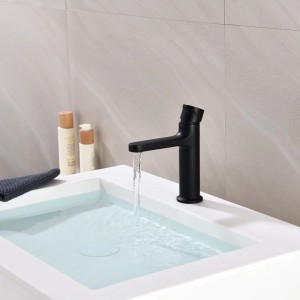 Mattschwarze Waschtischarmatur mit flachem Auslauf und Drehgriff, Wasser fließt in weißes Waschbecken.