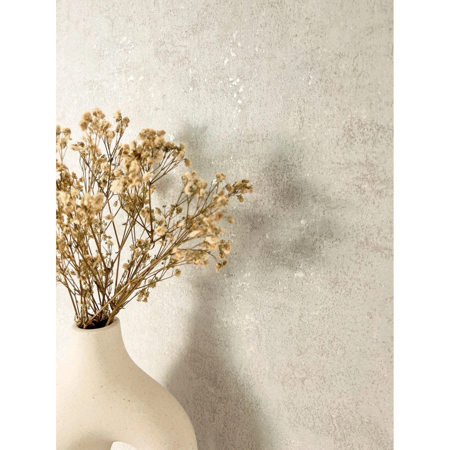 Moderne Vliestapete in Creme Betonoptik mit feiner Struktur, dekoriert mit einer Vase und Trockenblumen.
