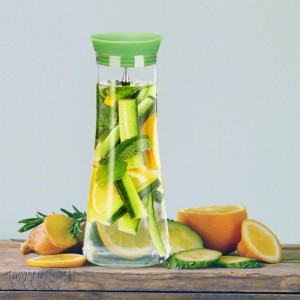 Glaskaraffe mit Siebeinsatz und Obst gefüllt. Karaffe aus Kristallglas mit Edelstahl-Elementen.