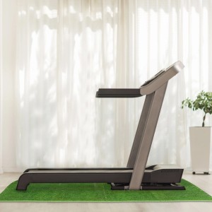 Grüne EVA Bodenschutzmatte mit Rasenmotiv unter einem Laufband. Stoßdämpfende Trittschalldämmung für Fitnessgeräte.