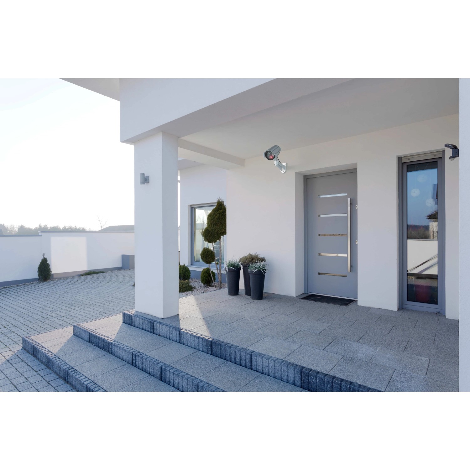 Basi Kamera Attrappe KA 300 in Silber mit LED-Blinklicht an Hauswand montiert.