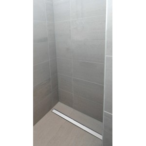 Schütte Duschrinne mit Edelstahl-Abdeckung in ebenerdiger Dusche mit grauen Fliesen.