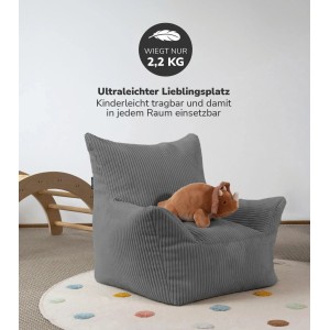 Anthrazitfarbener mokebo Kindersessel 'Pausenheld' aus Cord mit Dino-Kuscheltier auf einem Teppich.
