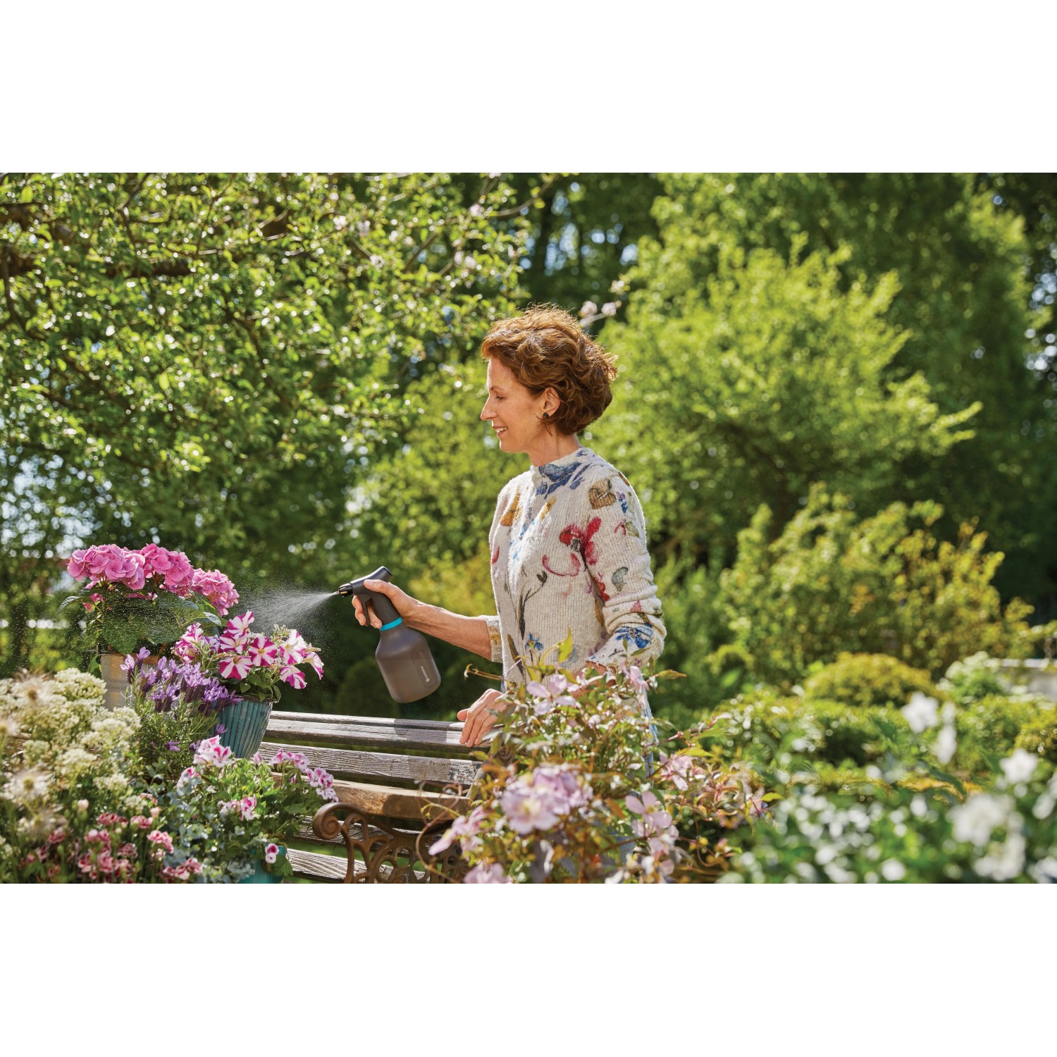 Frau benutzt Gardena Pumpsprüher 0,75 l zum Besprühen von Blumen.