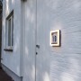 Moderne LED Hausnummerleuchte Alice mit Zahlenaufkleber an weißer Hauswand.