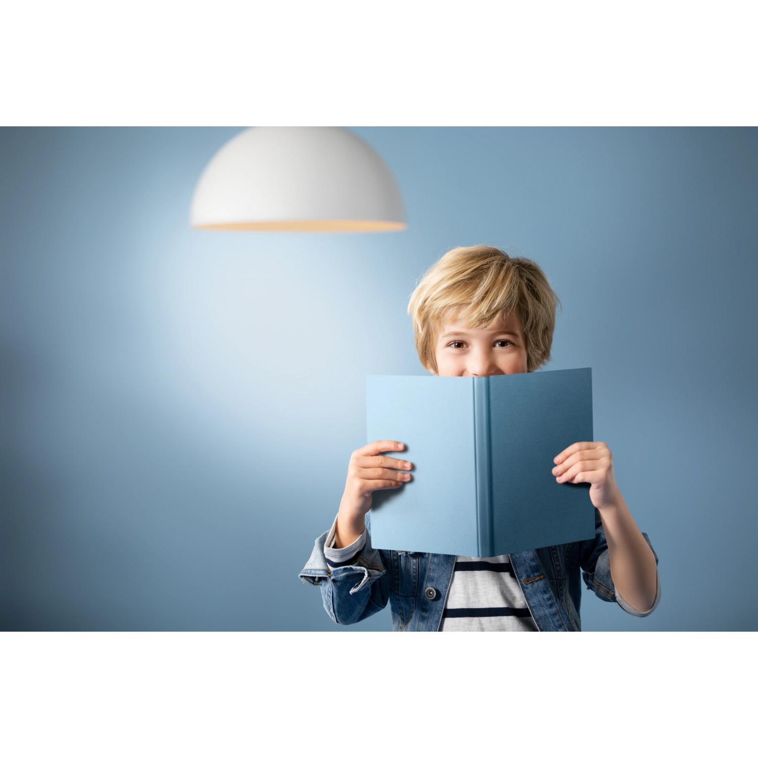 Junge liest unter Philips E27 LED Lampe. Glühlampenform, 10,5W, neutralweißes Licht.